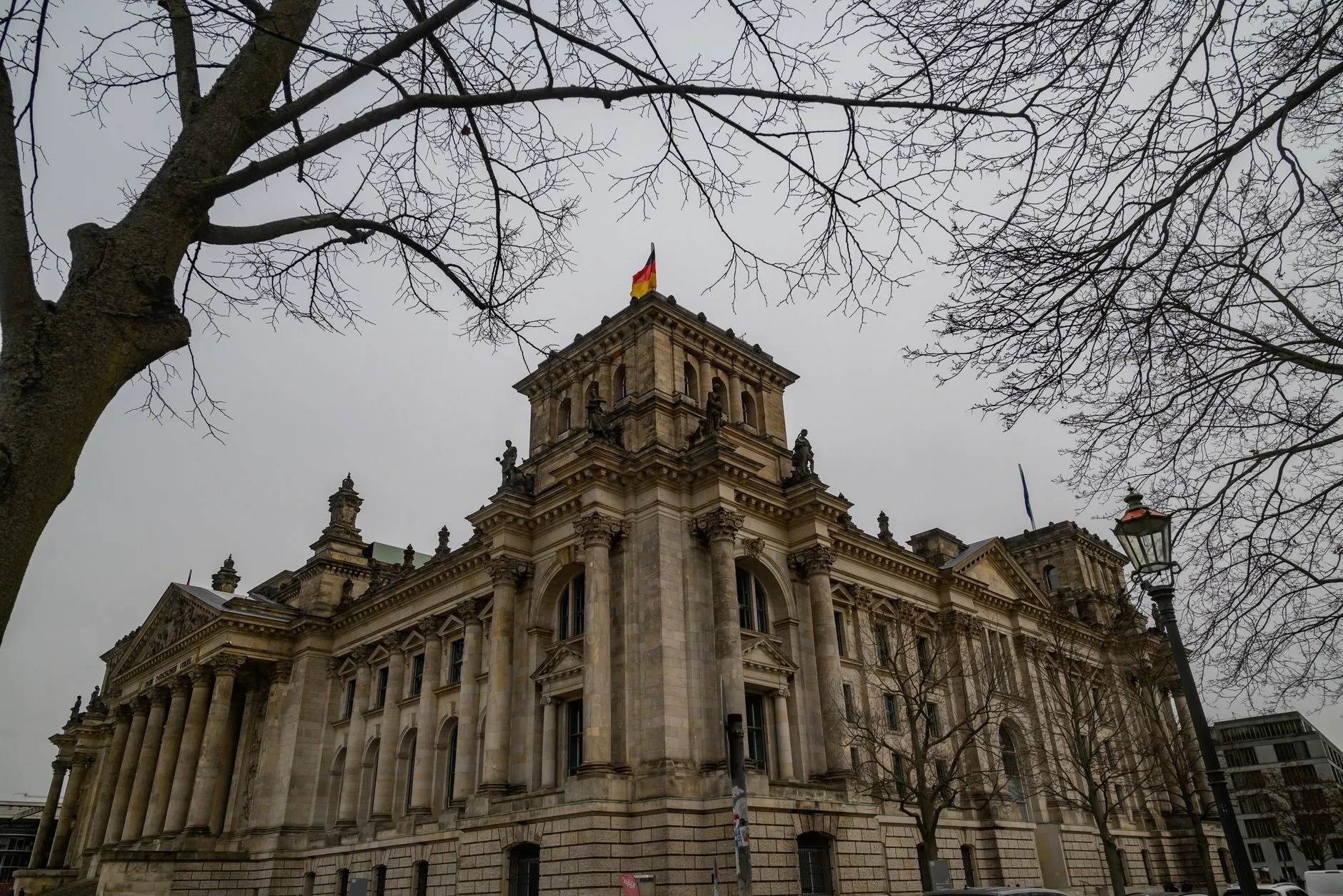 Budynek Reichstagu w Berlinie otoczony bezlistnymi drzewami