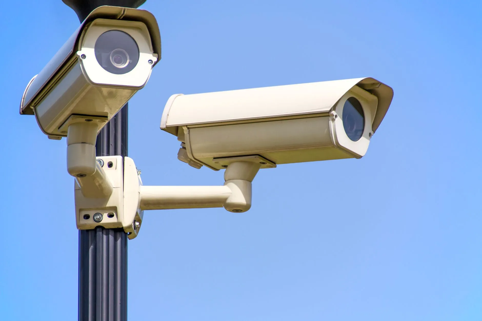 Dwie kamery monitoringu na słupie na tle błękitnego nieba