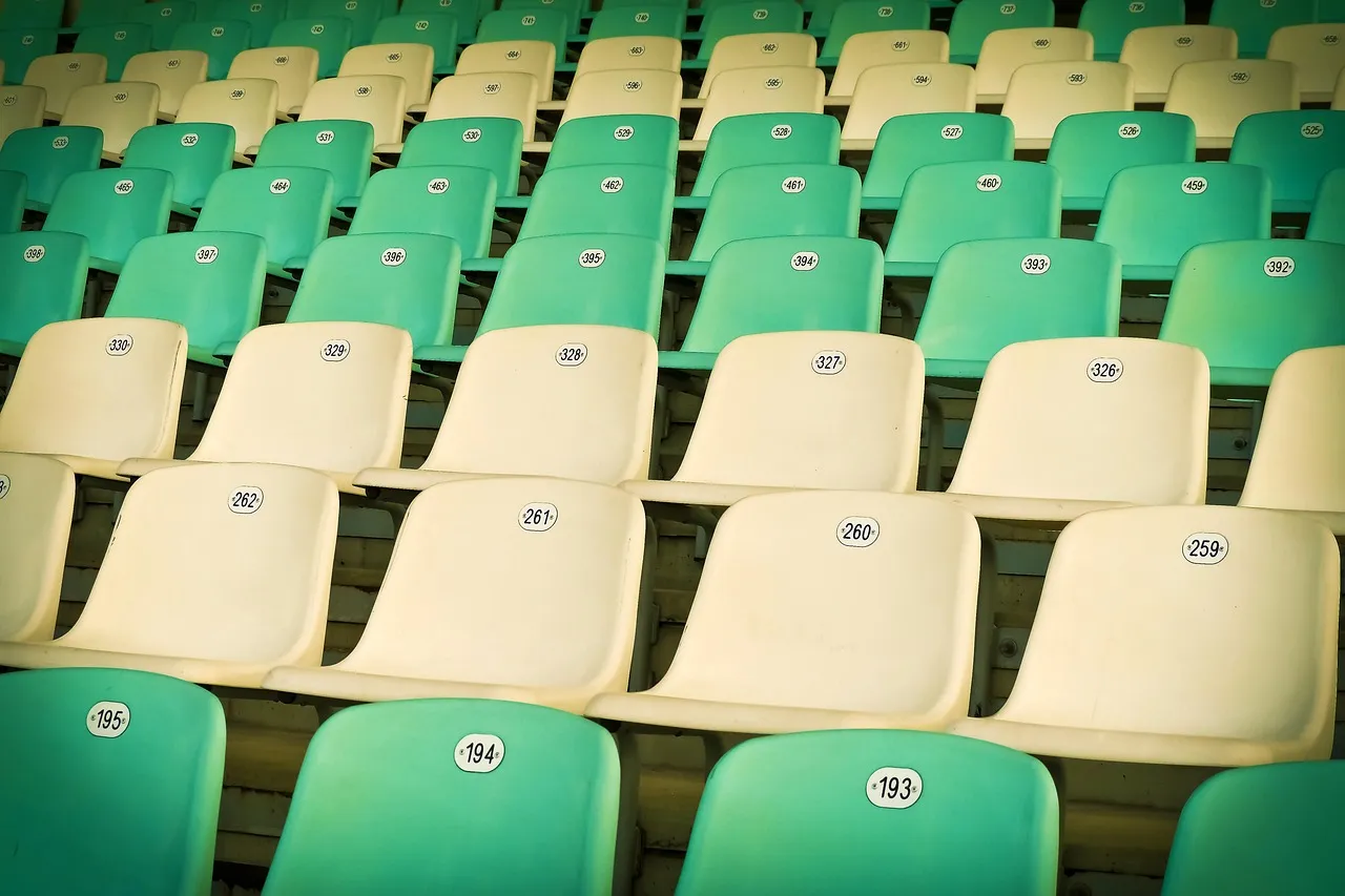 Zielone i kremowe krzesełka na pustych trybunach stadionu