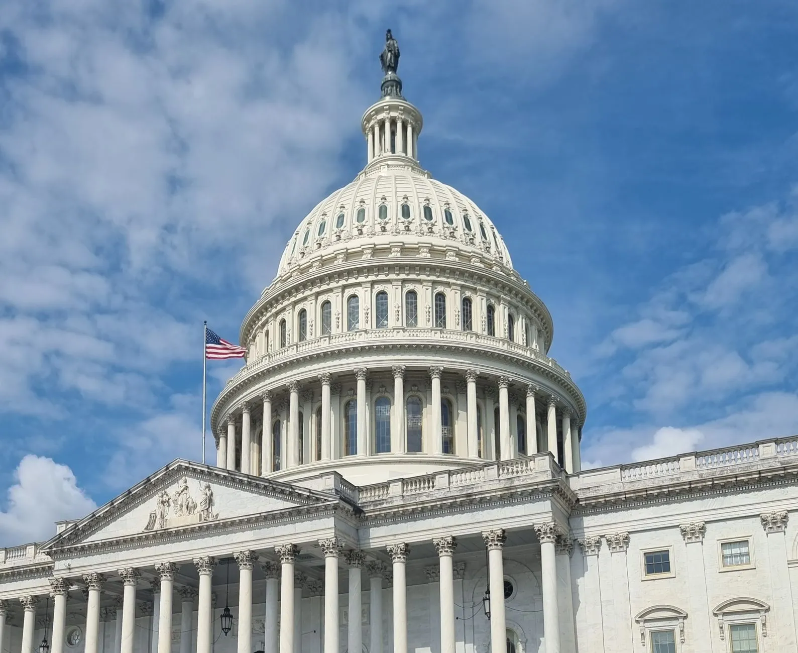 Kopuła Kapitolu USA z amerykańską flagą na tle nieba