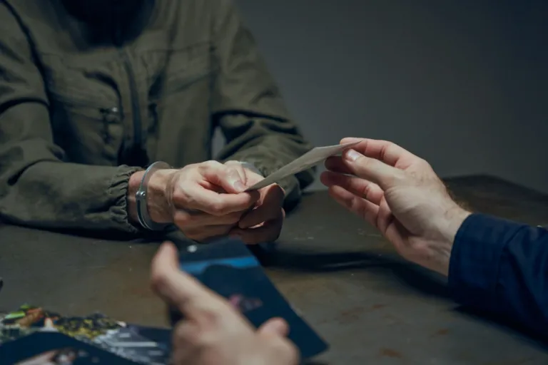 Zakuty w kajdanki mężczyzna przekazuje kartkę podczas przesłuchania