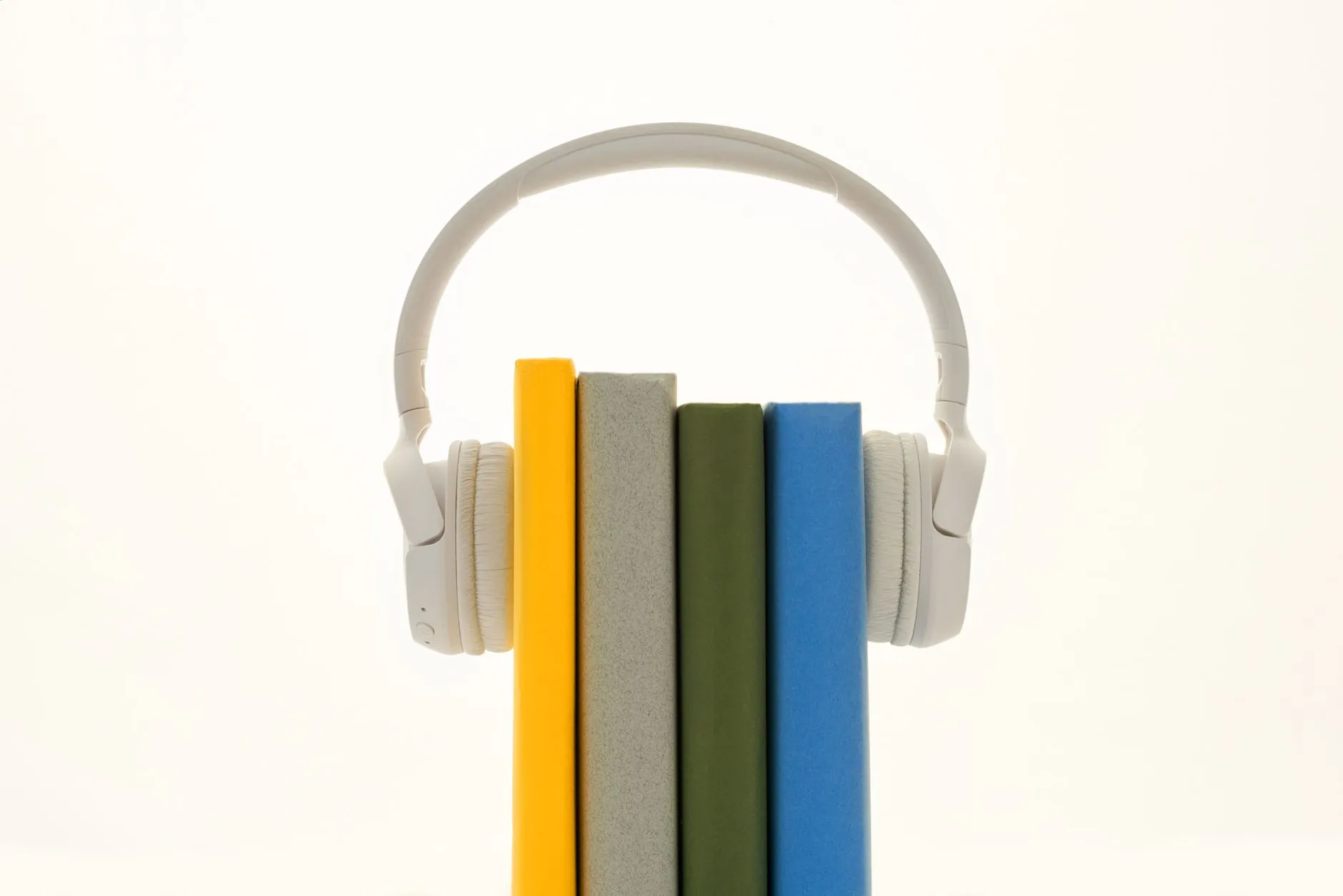 Białe słuchawki na czterech kolorowych książkach