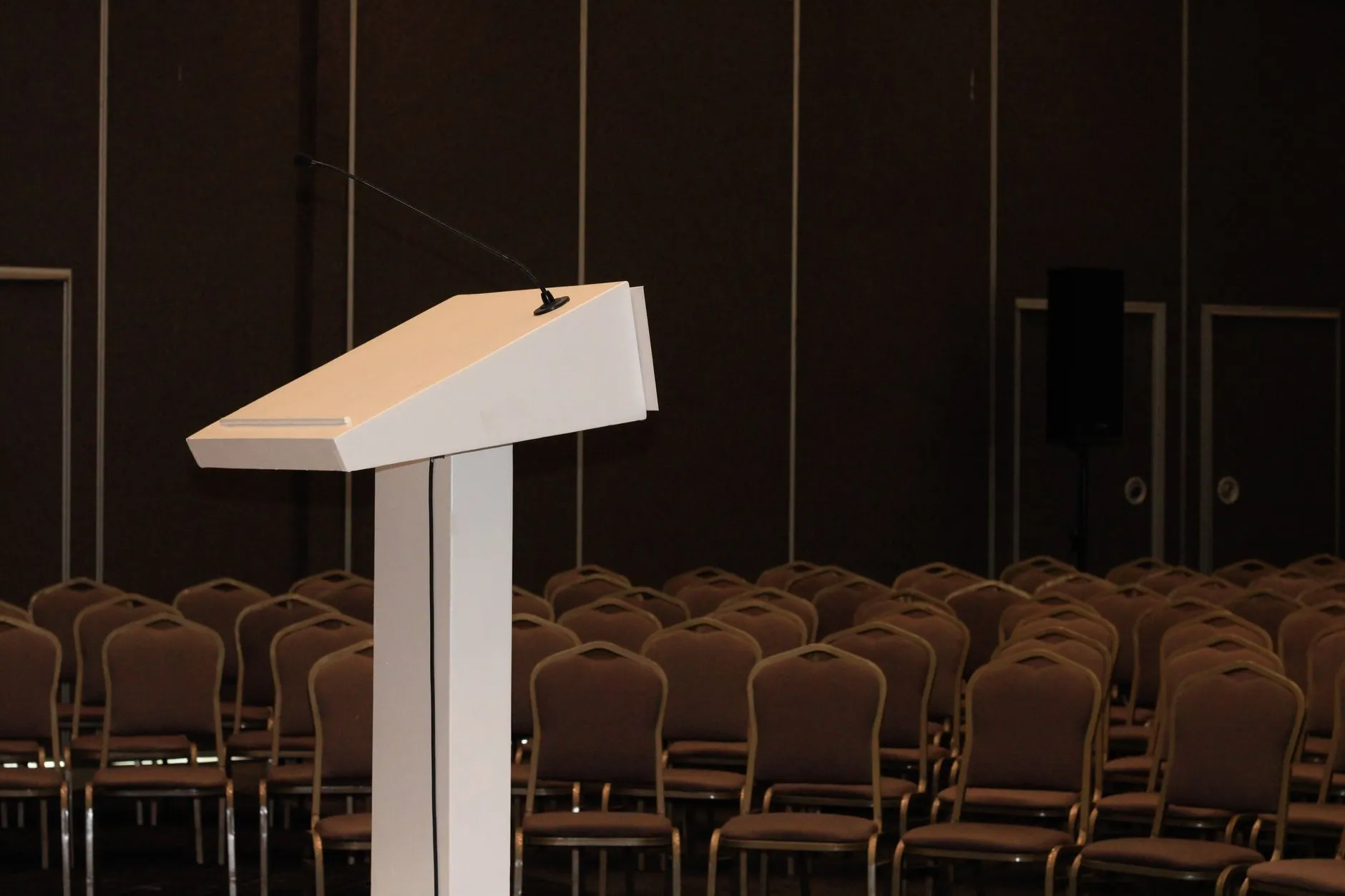 Mównica przed rzędami pustych krzeseł w sali konferencyjnej