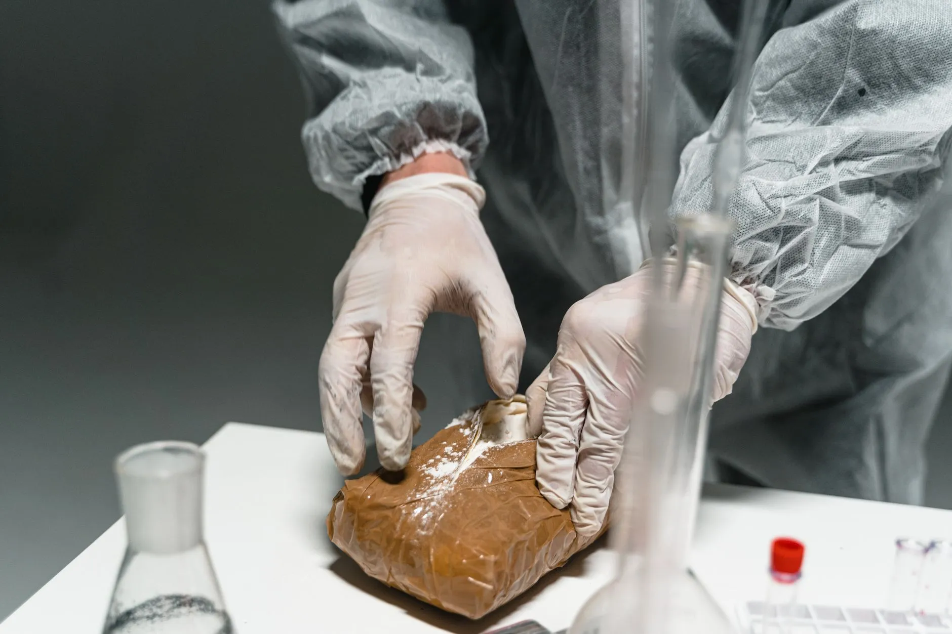 Ręce w rękawiczkach badają zabezpieczoną substancję w laboratorium