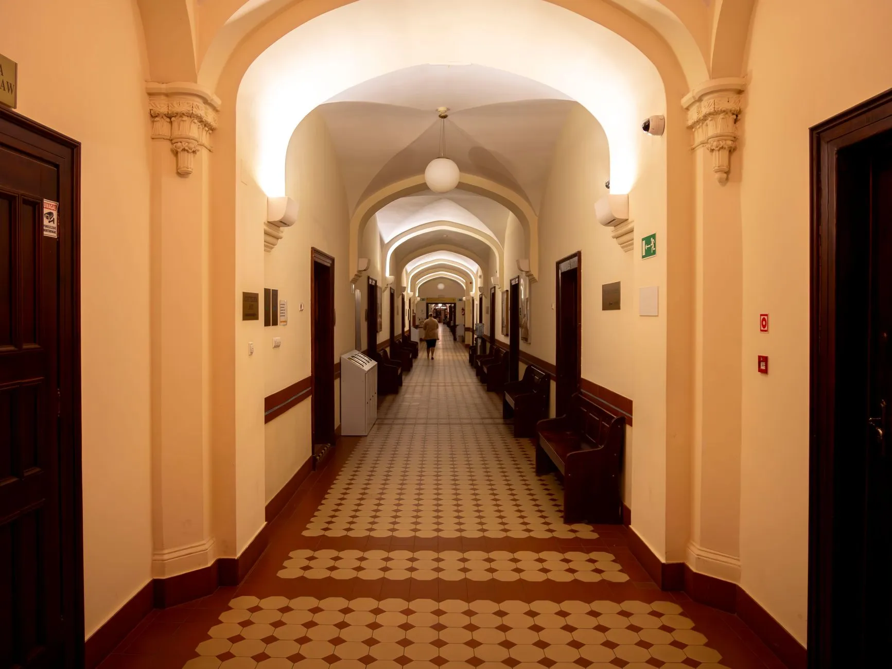 Korytarz zabytkowego sądu z arkadami i ławkami