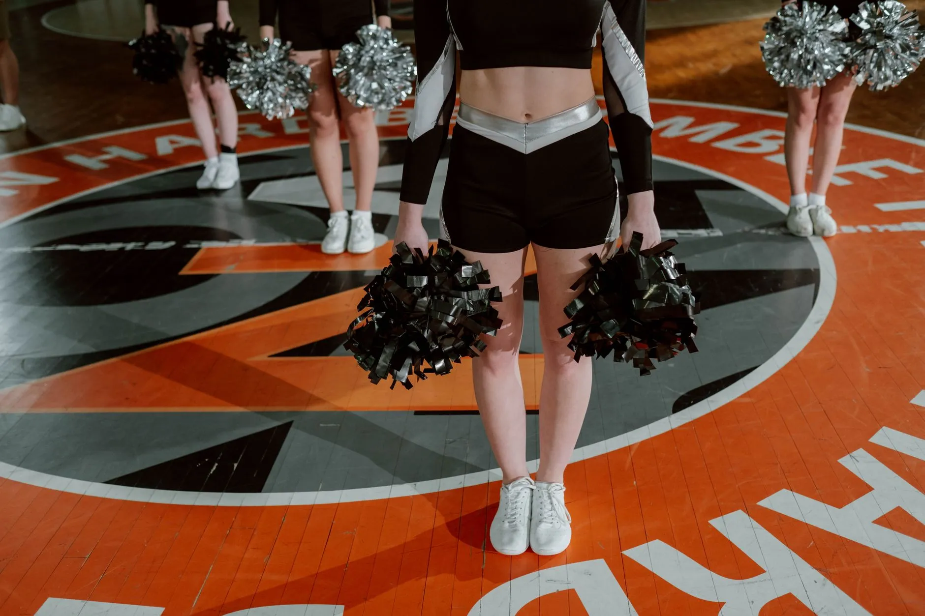 Cheerleaderki z pomponami podczas występu na hali sportowej