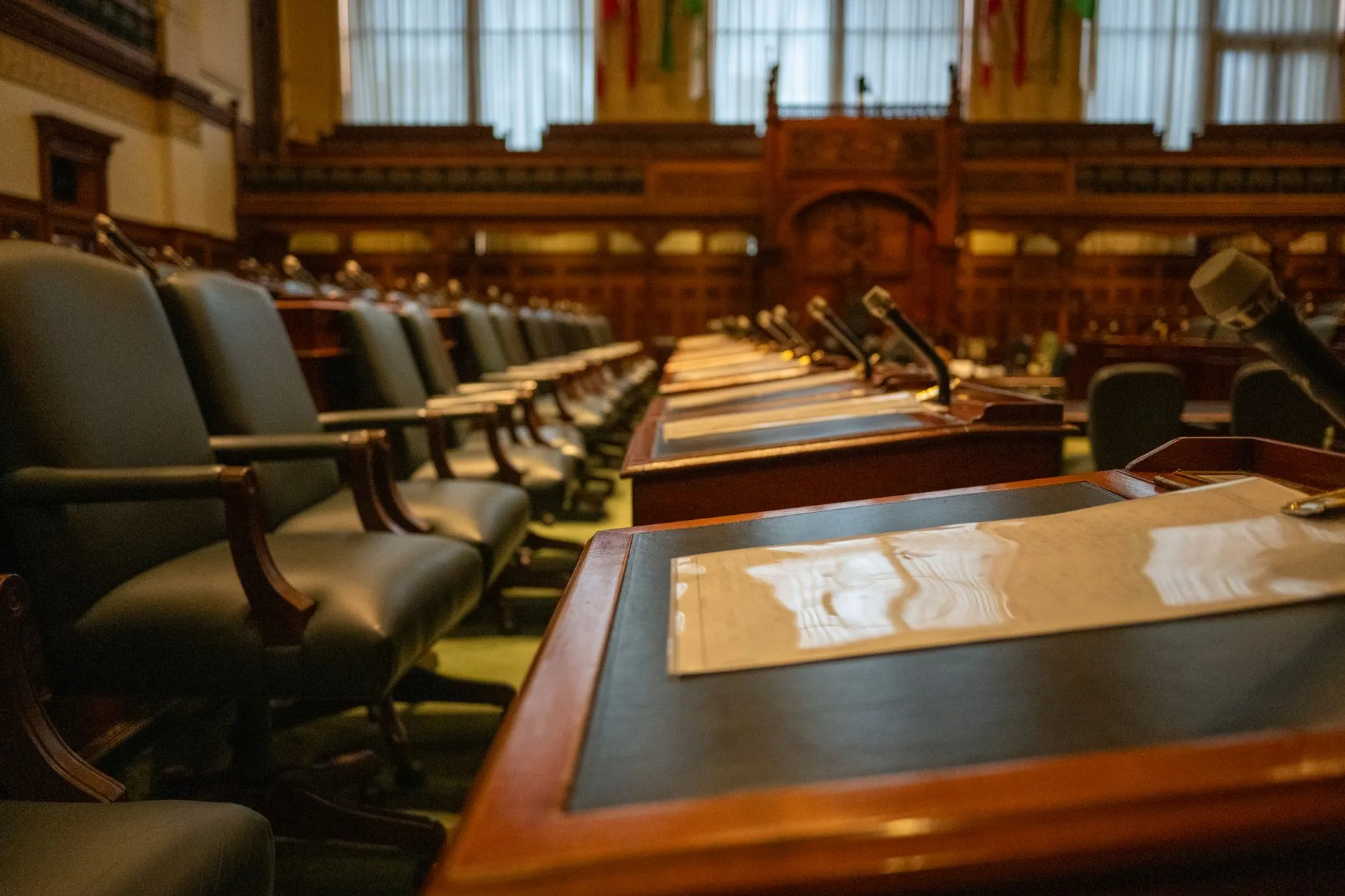 Pusta sala parlamentarna z rzędami biurek i mikrofonów